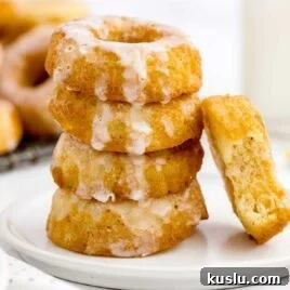 close up shot of Sour Cream Donuts topped with glaze and stacked on top of each other on a plate
