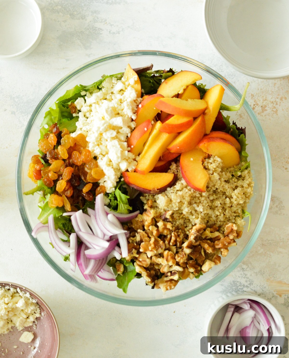 peaches, feta, quinoa, raisins, and red onions on mixed greens