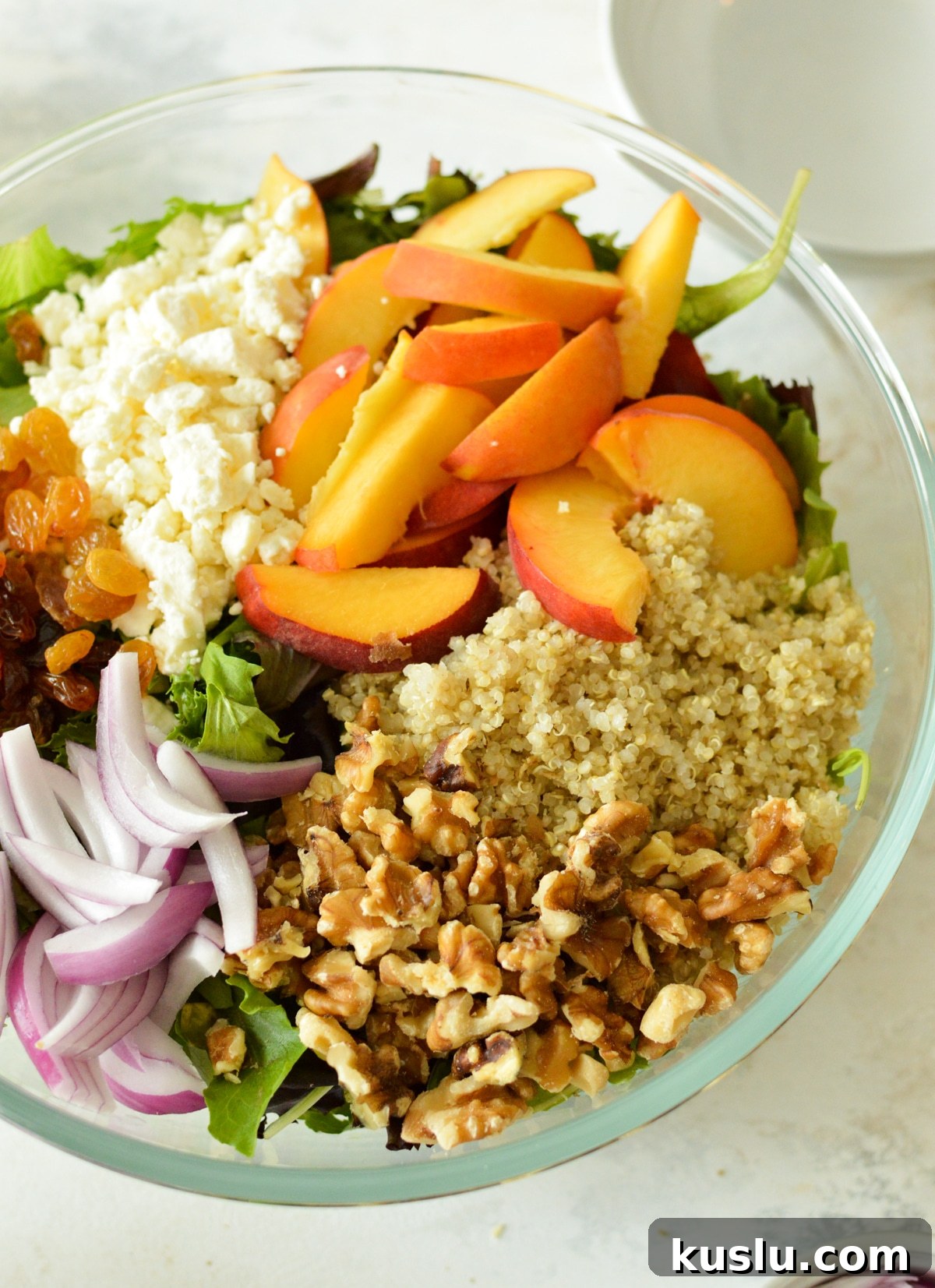 peaches, quinoa, walnuts, feta, and raisins on greens