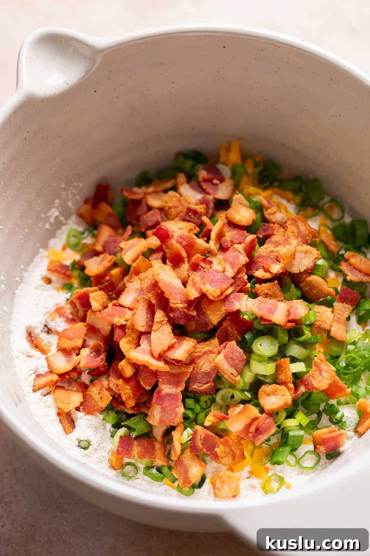 Bacon, Cheddar & Scallion Scones: Savory Breakfast Biscuits 4 A mixing bowl with the dry ingredients, bacon, cheese, and scallions before mixing.