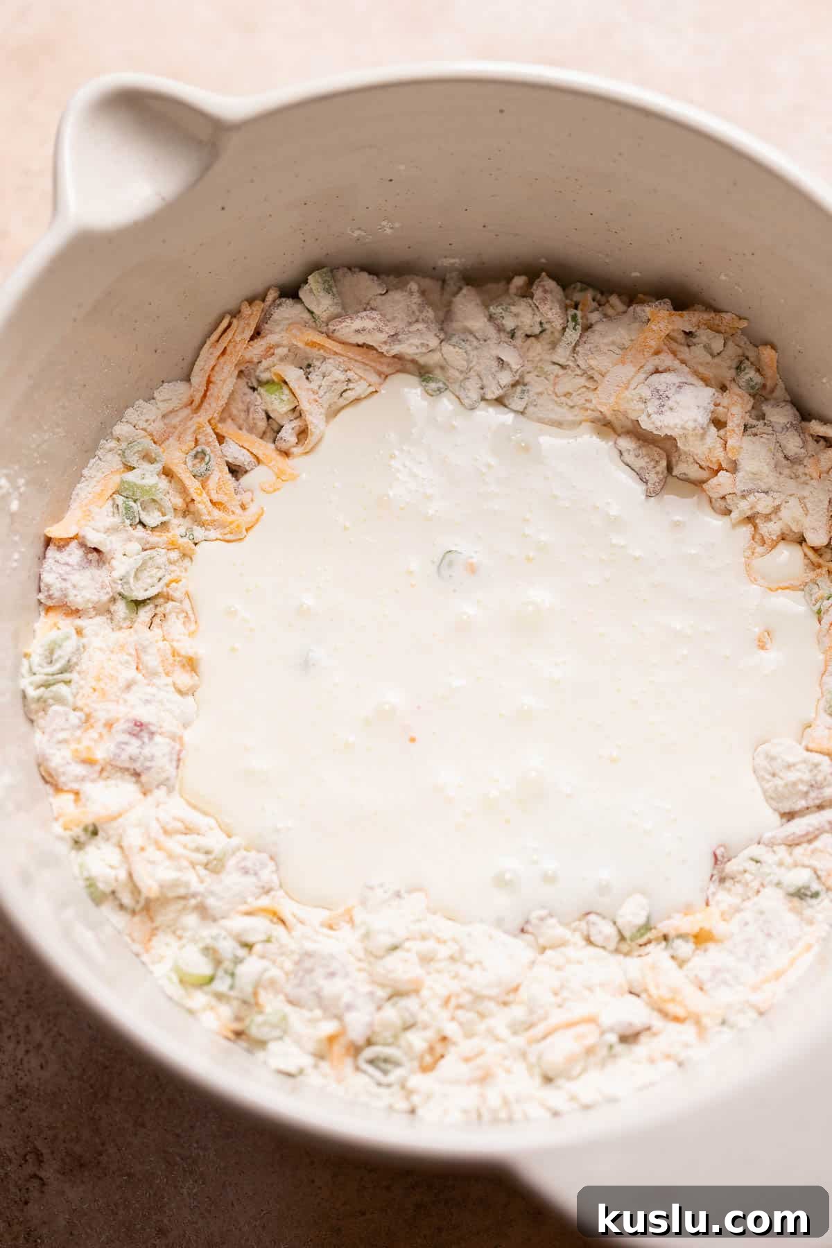 Bacon, Cheddar & Scallion Scones: Savory Breakfast Biscuits 5 A mixing bowl with the cream poured into the center of the dry ingredients.