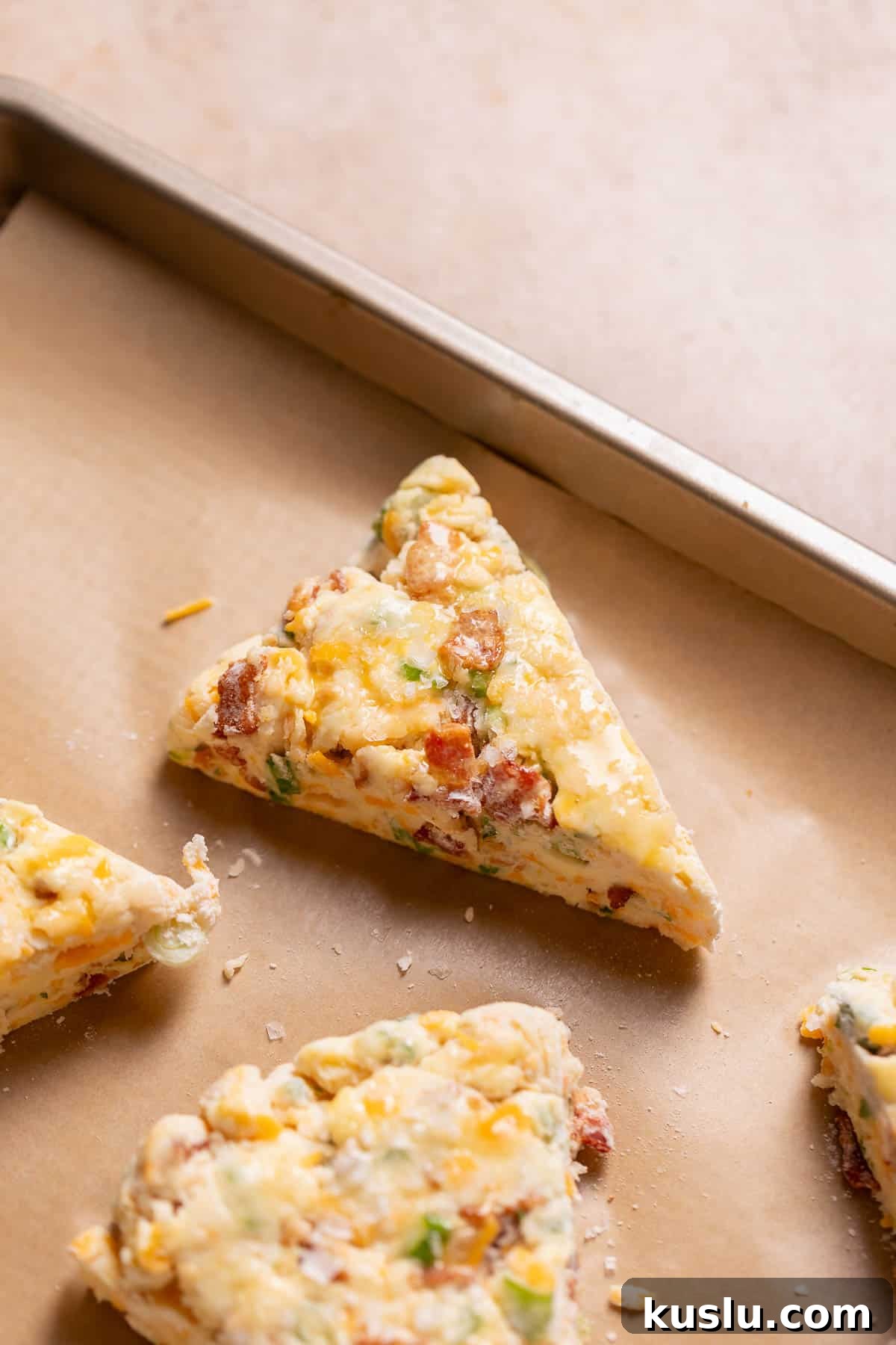 Bacon, Cheddar & Scallion Scones: Savory Breakfast Biscuits 9 Bacon cheddar scones on a baking tray brushed with egg wash before baking.
