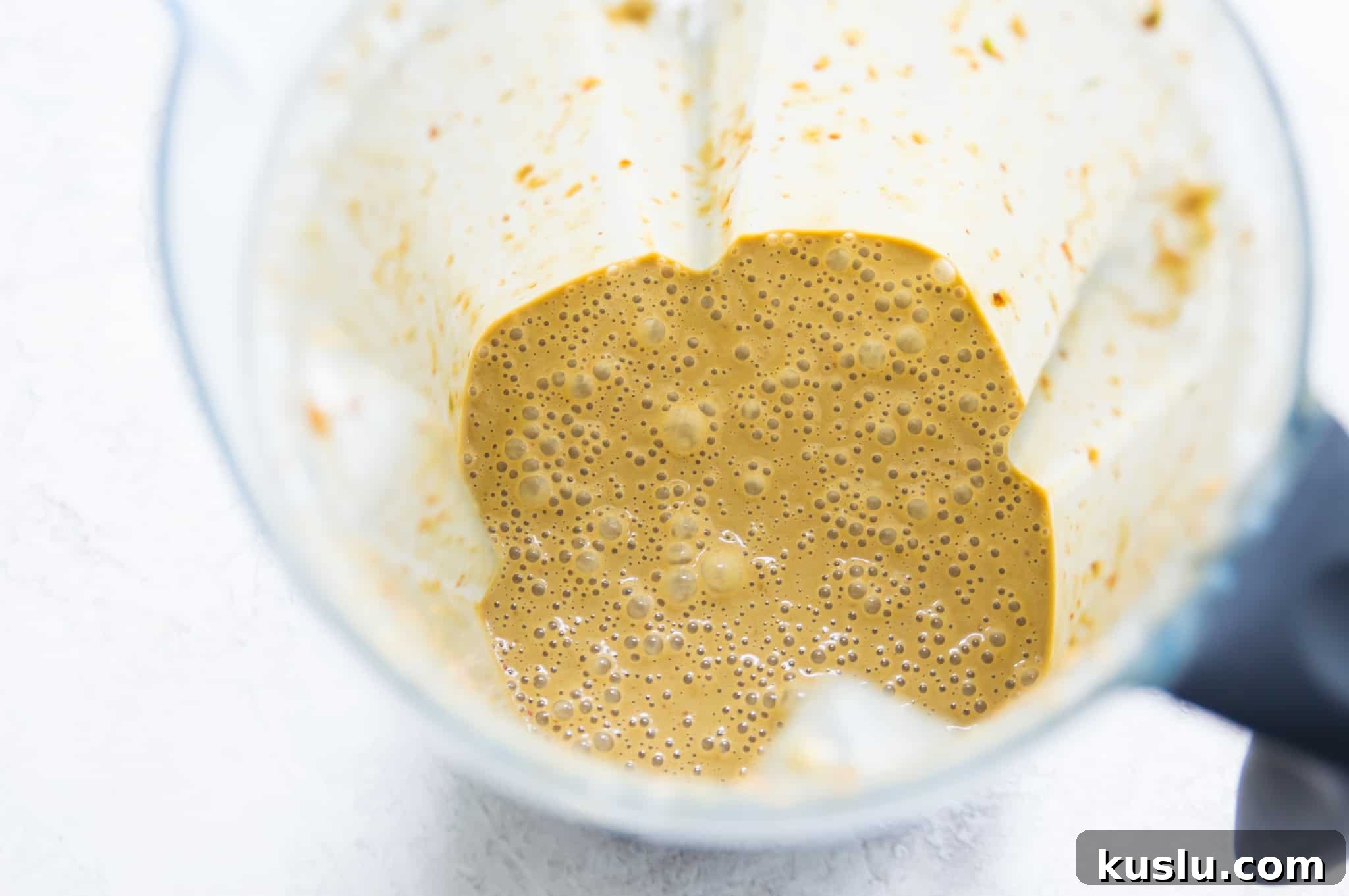 A blender with a brown creamy sauce in it.