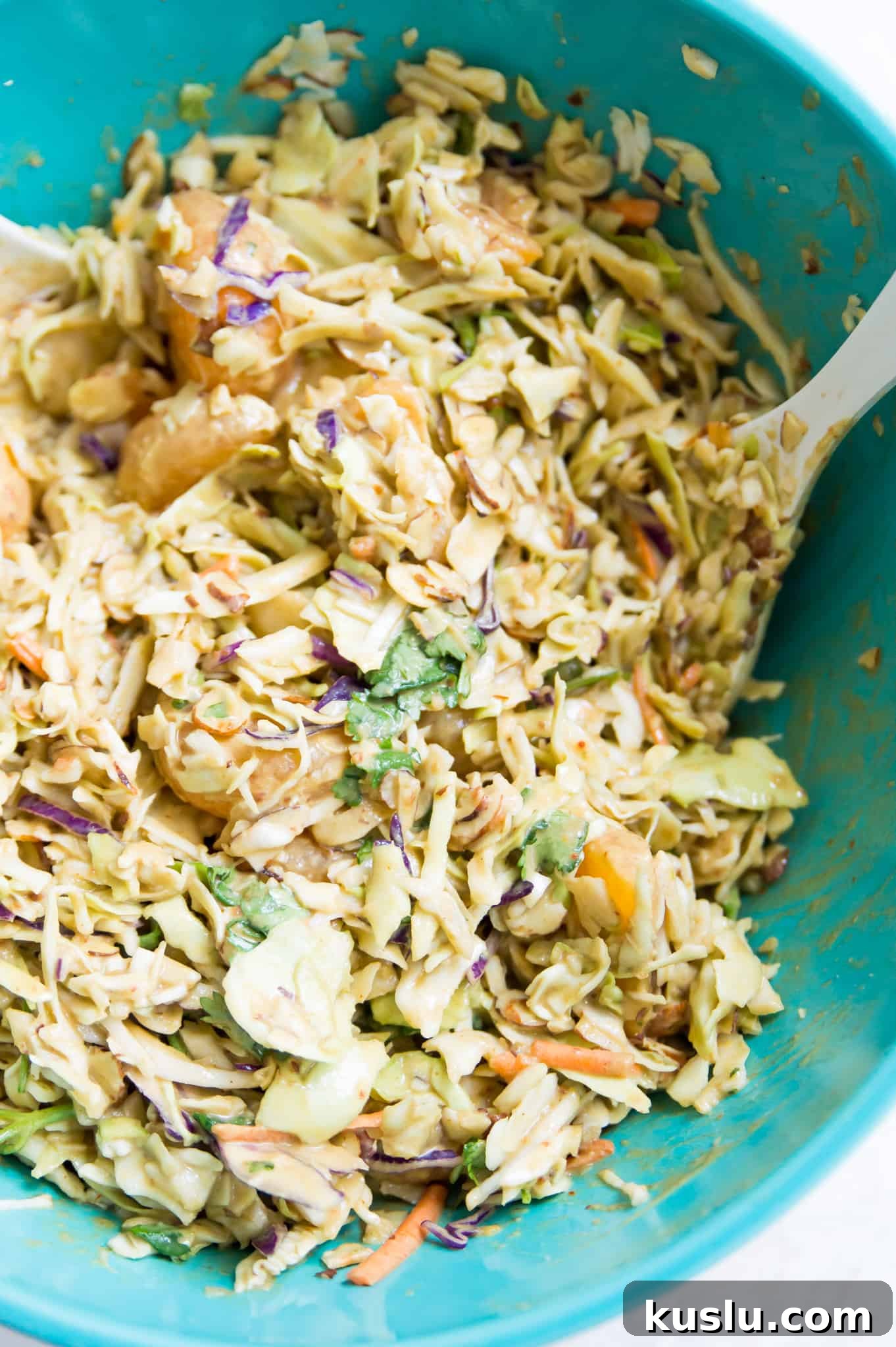 A bowl of coleslaw with a serving spoon in it.