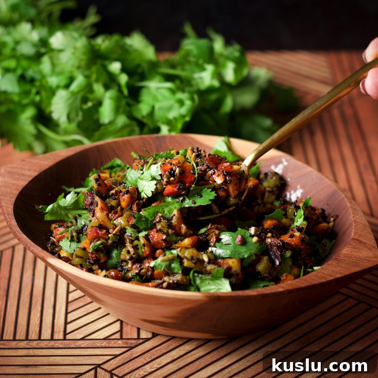 Someone lifting a spoonful of almond salsa from a wood bowl that's filled with the salsa. The bowl is sitting on a wood table with a bunch of fresh cilantro in the background.