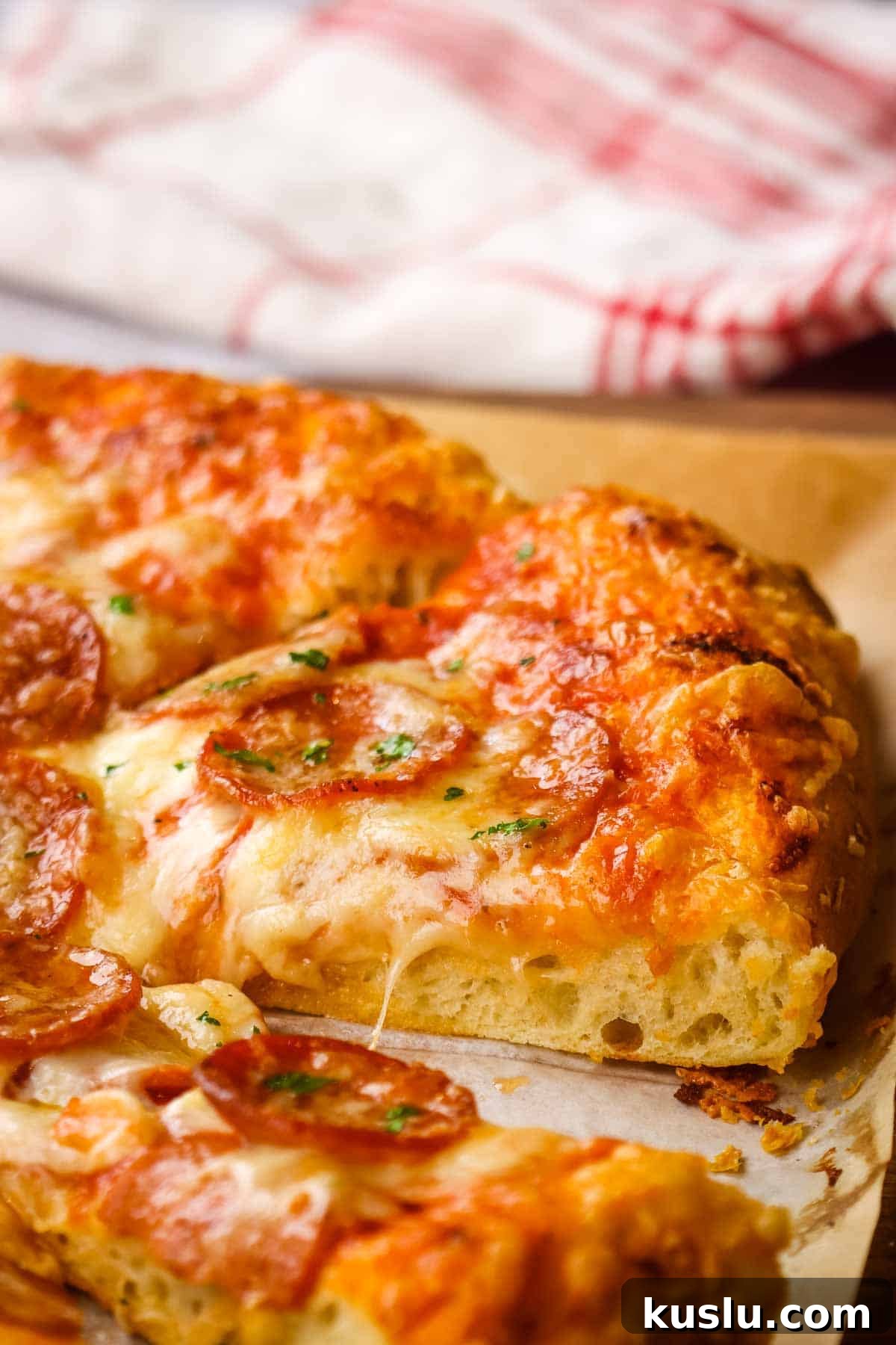 How to Make Thick Crust Pizza at Home: Crispy Edge, Chewy Center 2 Side view of a slice of thick crust pizza with pepperoni.