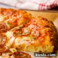 How to Make Thick Crust Pizza at Home: Crispy Edge, Chewy Center 19 Side view of a slice of thick crust pizza with pepperoni.
