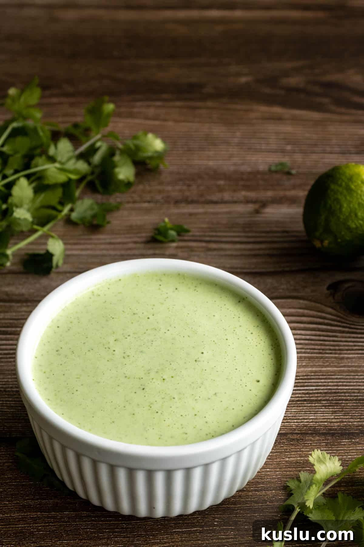 Cilantro Lime Crema: Creamy Sauce Recipe for Tacos & Bowls 8 Cilantro lime crema in a bowl on a table.