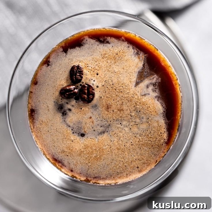 Overhead view of a gin espresso martini, garnished with 3 coffee beans, on a grey napkin.