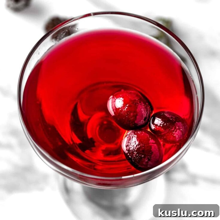 A cranberry gimlet garnished with 3 cranberries.