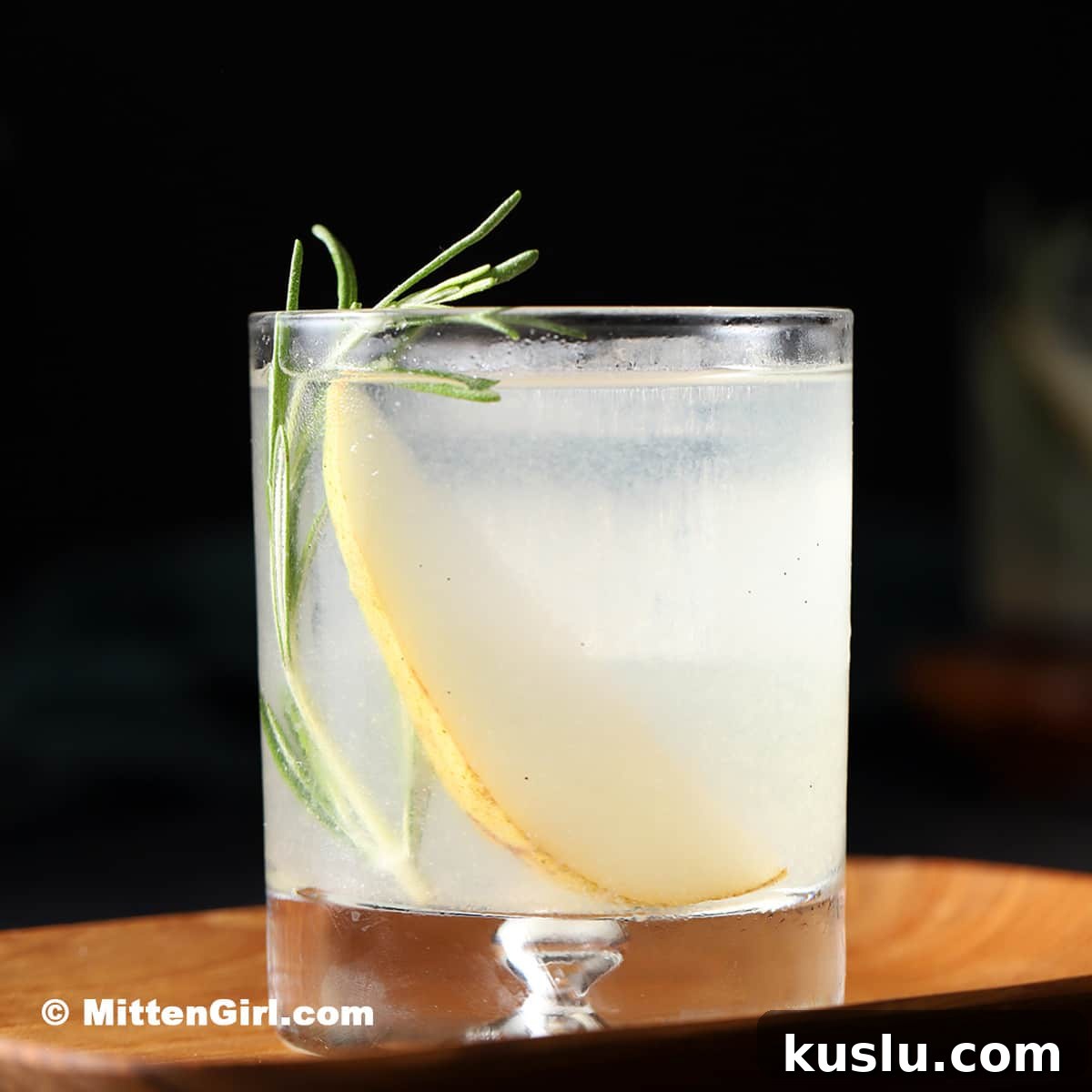 A pear gin and rosemary cocktail on a black background.