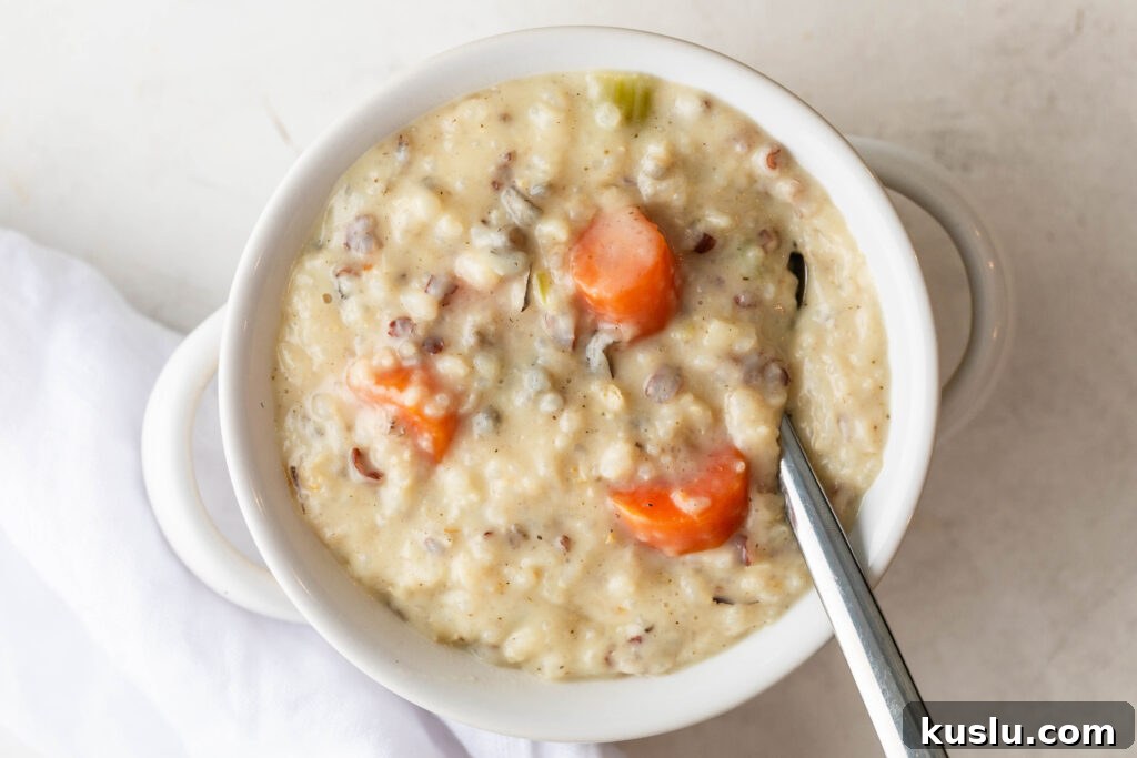 bowl of creamy chicken and rice with a silver spoon and a white napkin