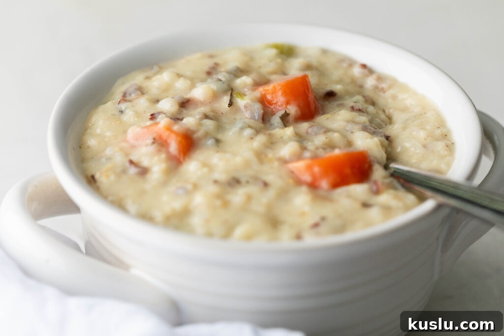 bowl of creamy chicken and rice with a silver spoon and a white napkin
