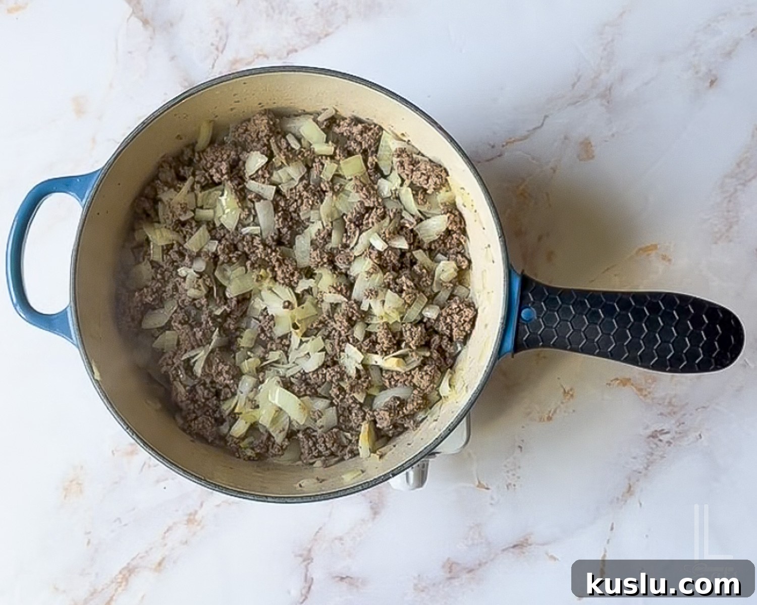 Walking Taco Casserole: Cheesy Taco Bake with Crunchy Nacho Topping 6 ground beef and onions cooking in a large skillet.