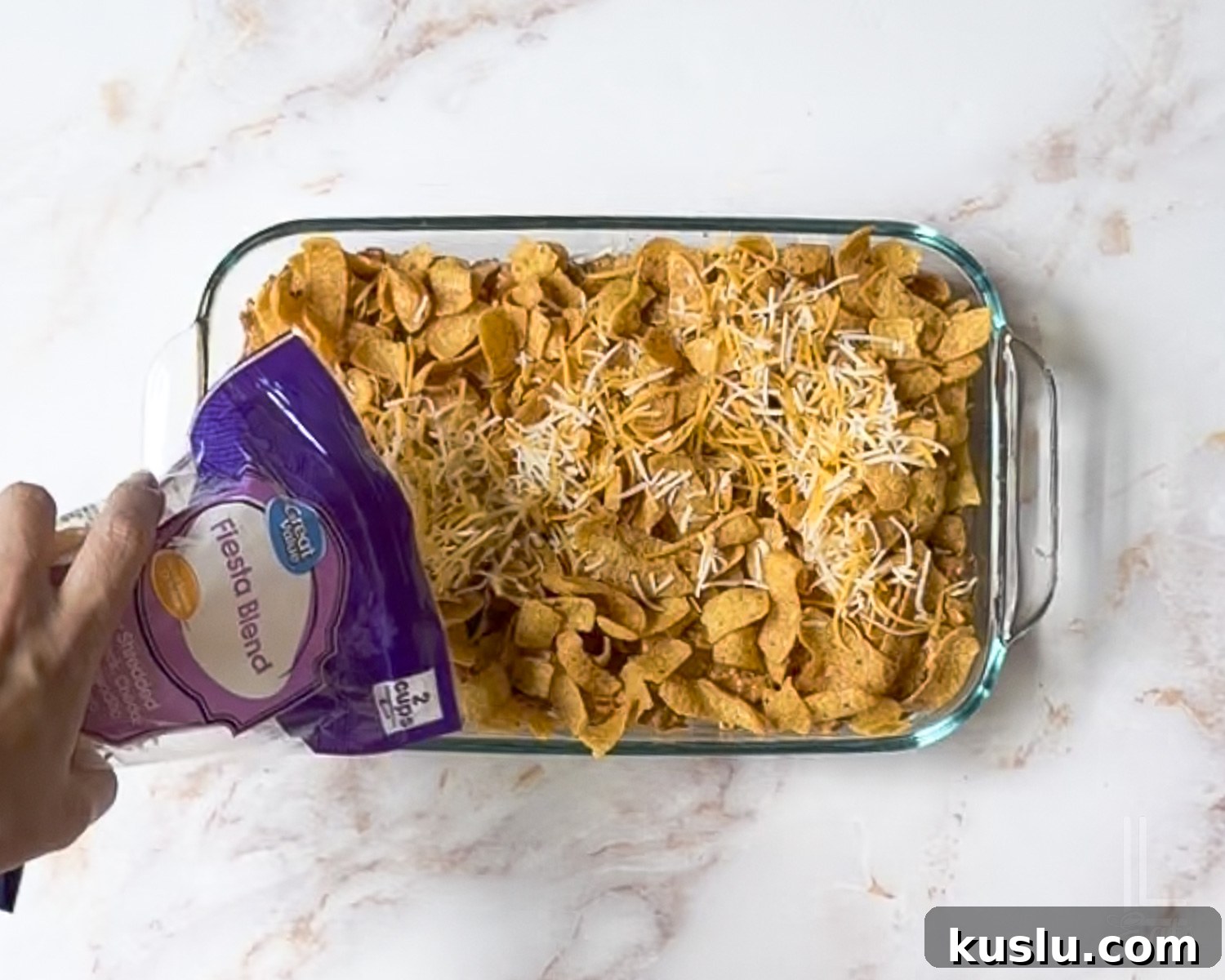 Walking Taco Casserole: Cheesy Taco Bake with Crunchy Nacho Topping 9 adding shredded cheese to the top of the walking taco casserole before baking.