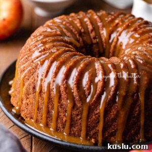 Homemade apple bundt cake with brown sugar glaze surrounded by an apple and chef's knife on dark wood background.