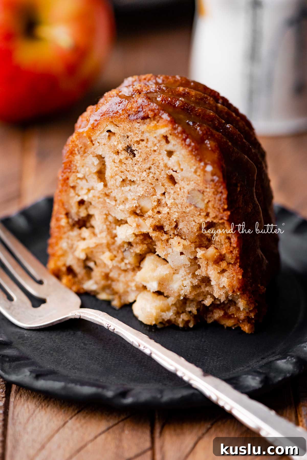 Slice of homemade apple bundt cake on dark wood background | © Beyond the Butter®
