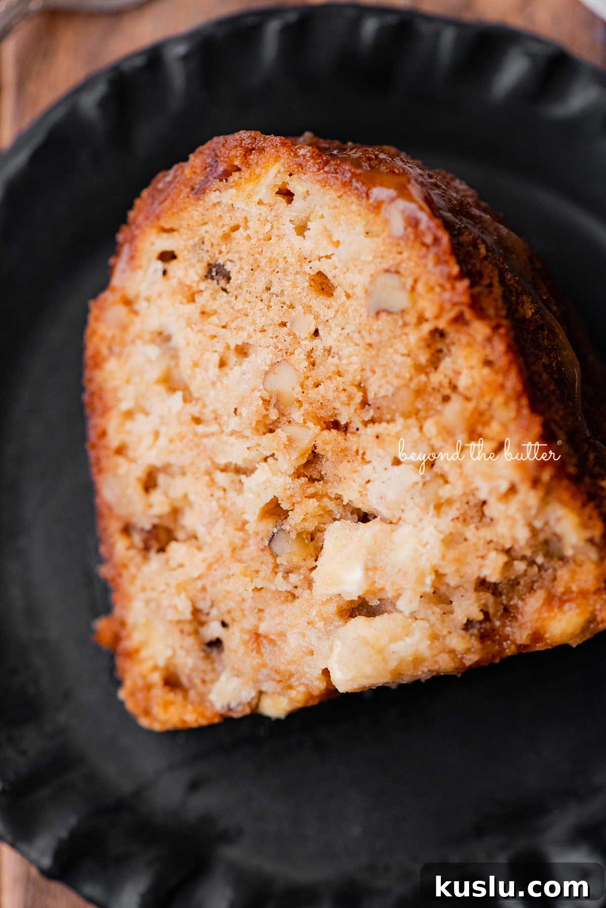 Slice of homemade apple bundt cake on dark wood background | © Beyond the Butter®