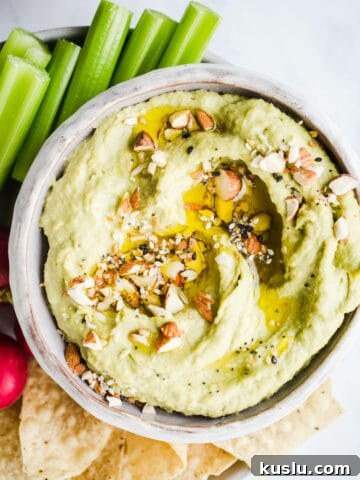 Green hummus in a bowl with veggies.