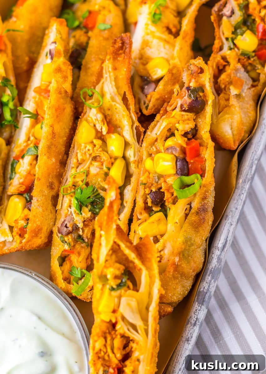 Southwestern Egg Rolls Copycat Recipe — Chili’s-Style Appetizer 2 cut southwestern egg rolls on a metal tray with a glass bowl of cilantro sour cream on the side