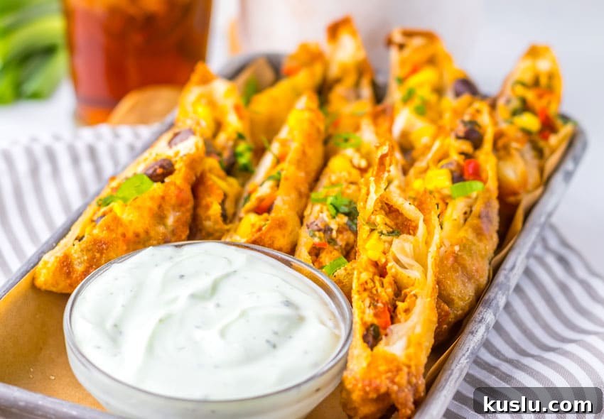 Southwestern Egg Rolls Copycat Recipe — Chili’s-Style Appetizer 7 cut southwestern egg rolls on a metal tray with a glass bowl of cilantro sour cream on the side