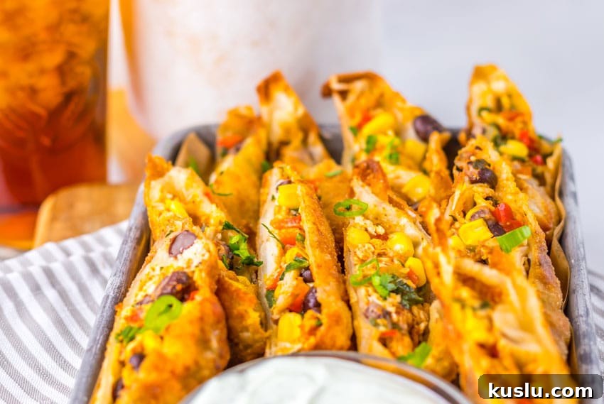 Southwestern Egg Rolls Copycat Recipe — Chili’s-Style Appetizer 8 cut southwestern egg rolls on a metal tray with a glass bowl of cilantro sour cream on the side
