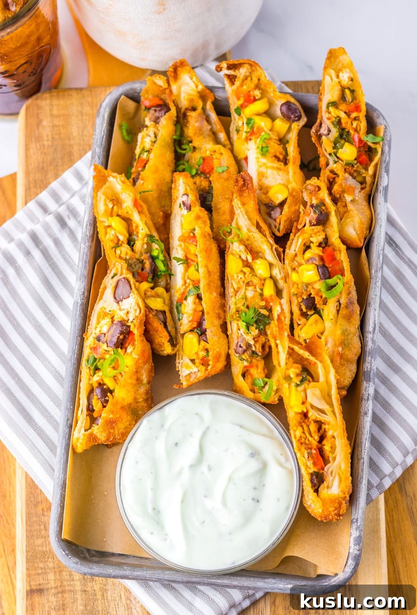 Southwestern Egg Rolls Copycat Recipe — Chili’s-Style Appetizer 9 cut southwestern egg rolls on a metal tray with a glass bowl of cilantro sour cream on the side