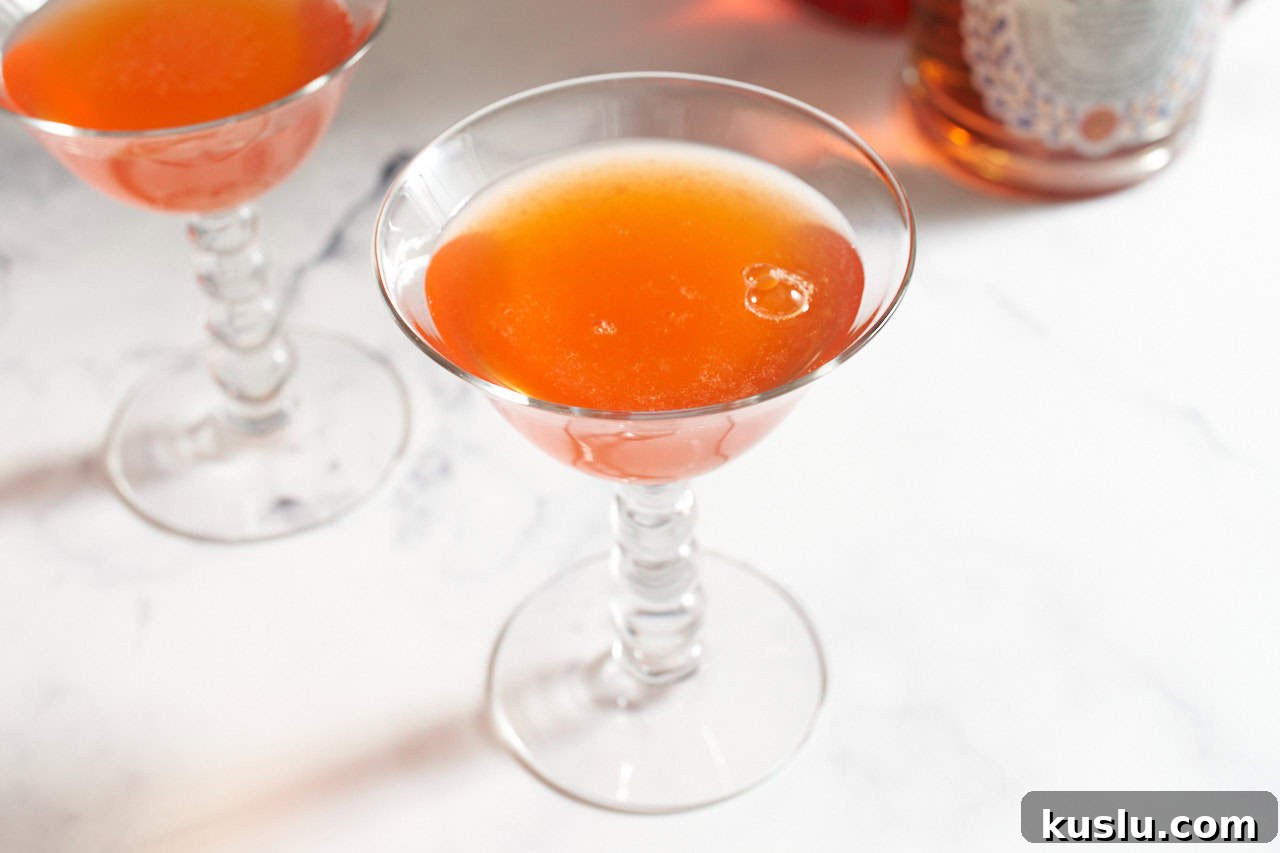 Two paper plane cocktails with bottles of liquor in the background.