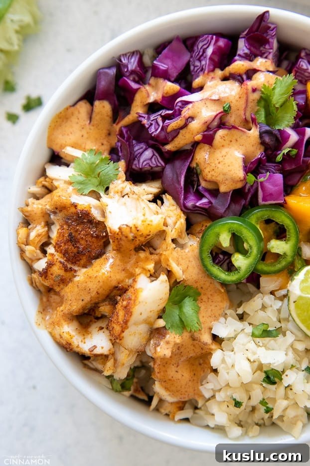 taco bowl overhead closeup of a paleo fish taco bowl with red cabbage slaw, baked barramundi and jalapeños on cauliflower rice