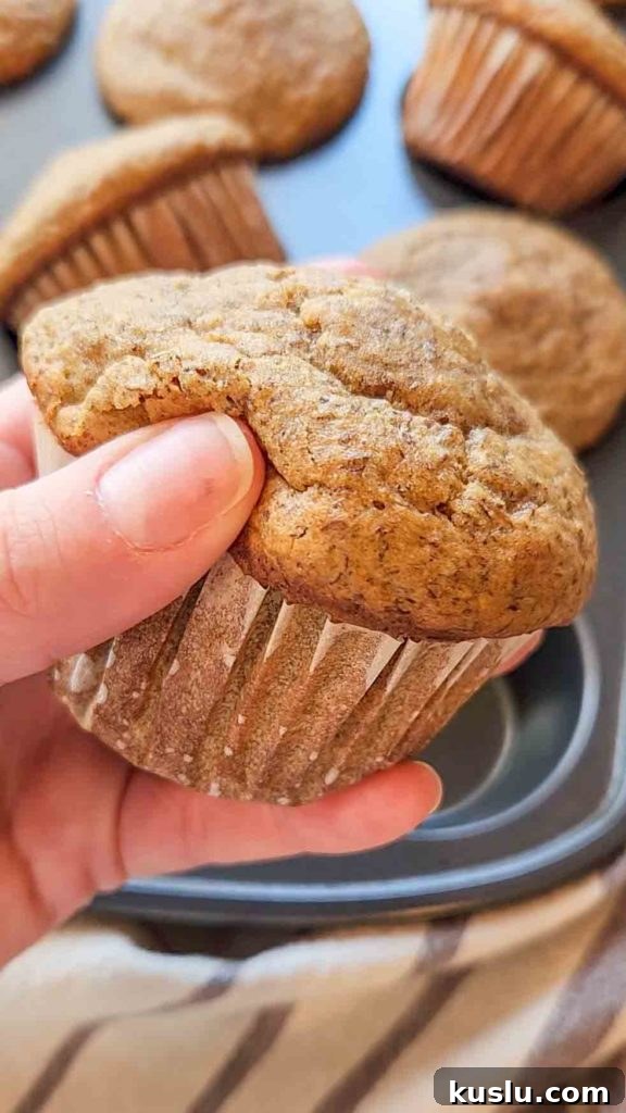 Gluten-Free Bran Muffin Recipe: Moist, Fluffy & Fiber-Rich 2 a hand gently squishes a gluten free bran muffin to show how soft it is.