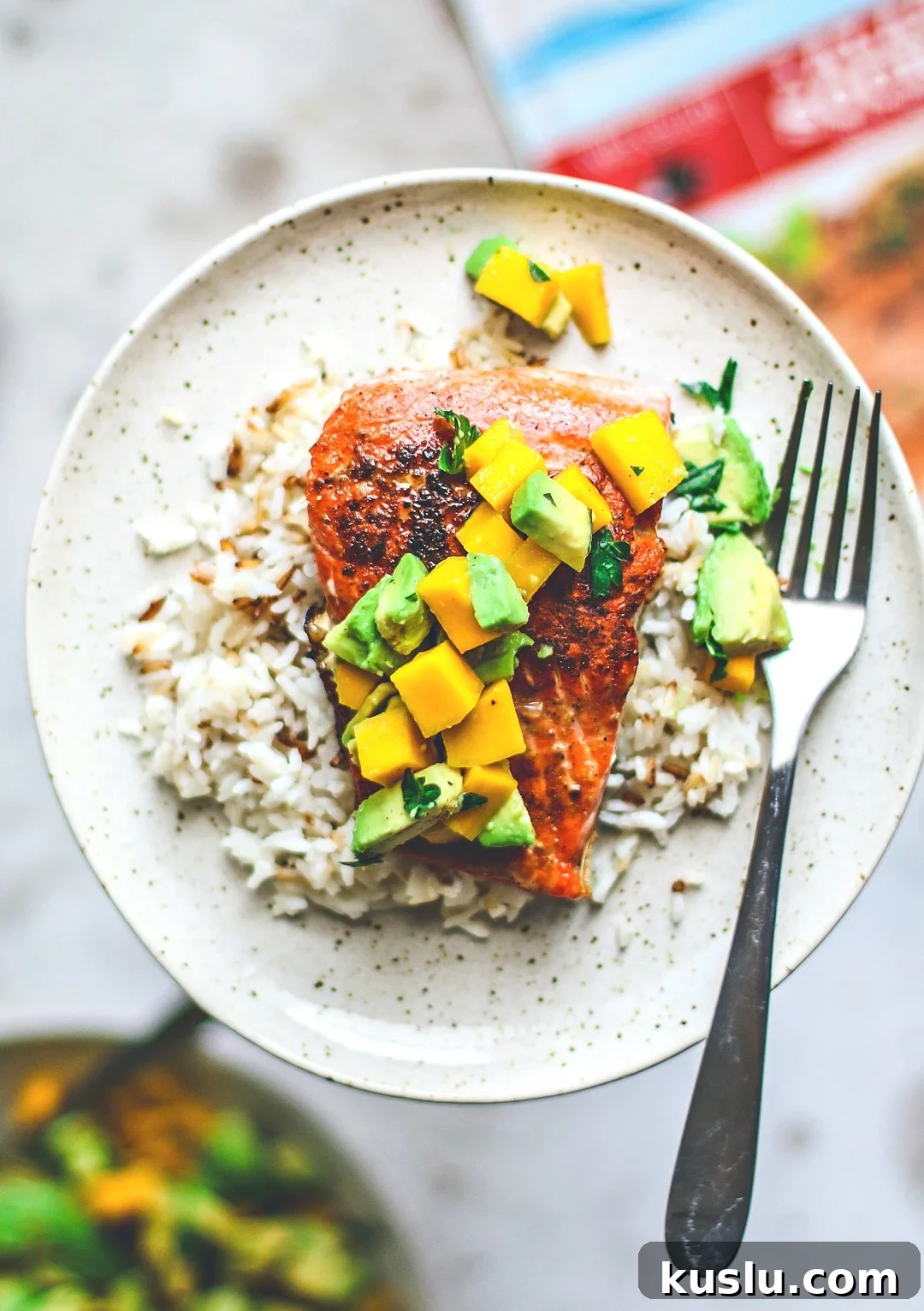 Pan-Seared Salmon with Fresh Avocado Mango Salsa 2 Close up of pan-seared salmon on plate over rice and topped with mango and avocado salsa.