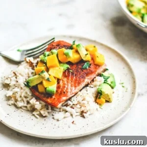 Pan-Seared Salmon on plate over rice and topped with mango and avocado salsa.