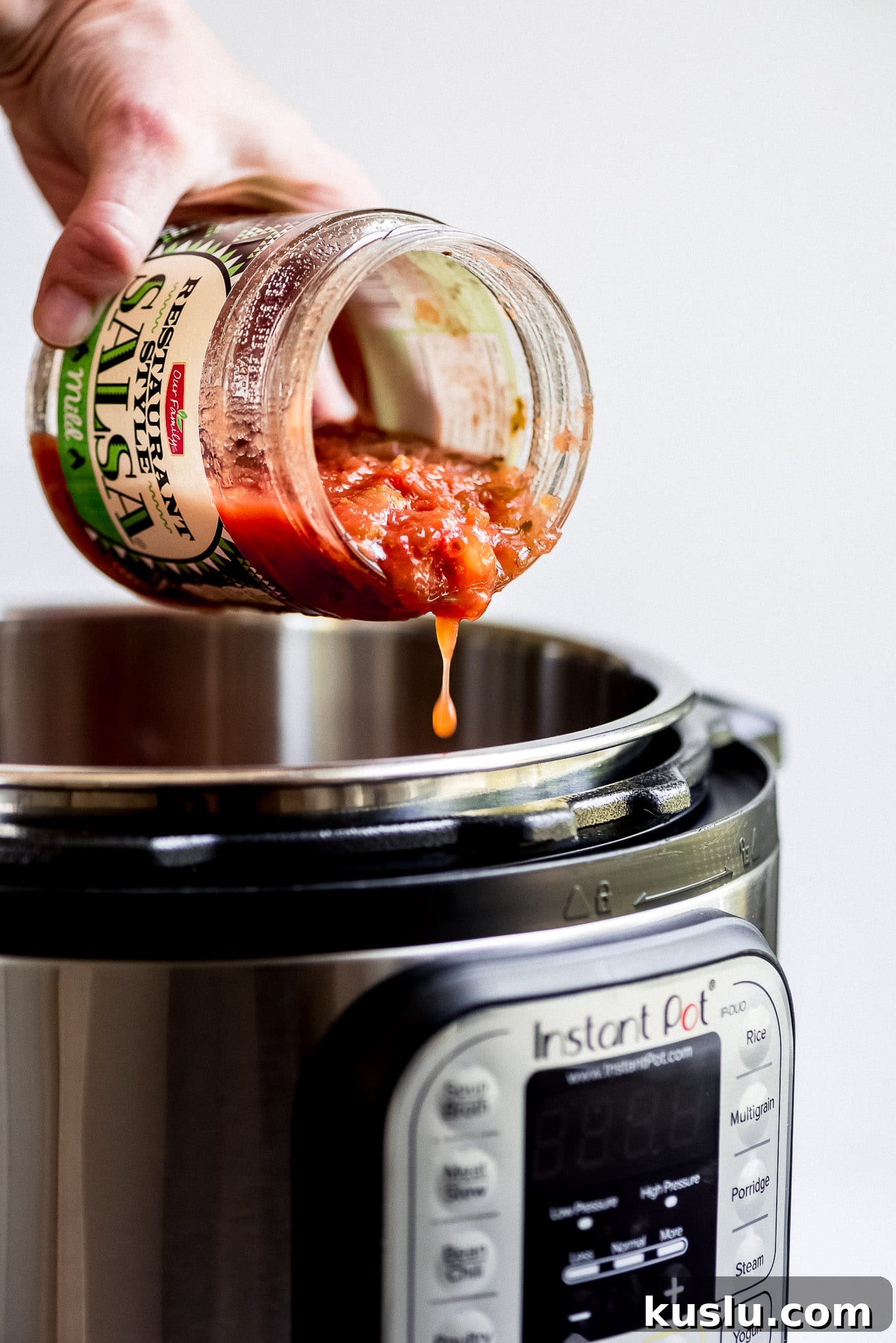 Pouring salsa into Instant Pot Pouring salsa out of a jar and into the Instant Pot for Salsa Chicken Tacos.
