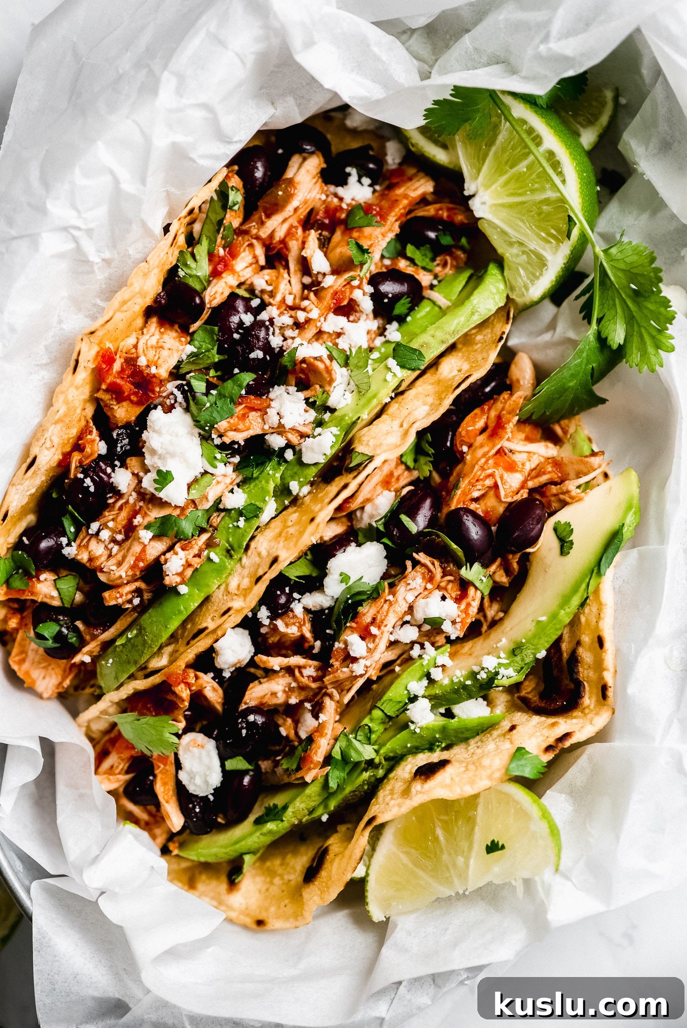 Close up of Salsa Chicken Tacos Close up shot of Instant Pot Salsa Chicken Tacos topped with avocado, black beans, cilantro, and cheese.