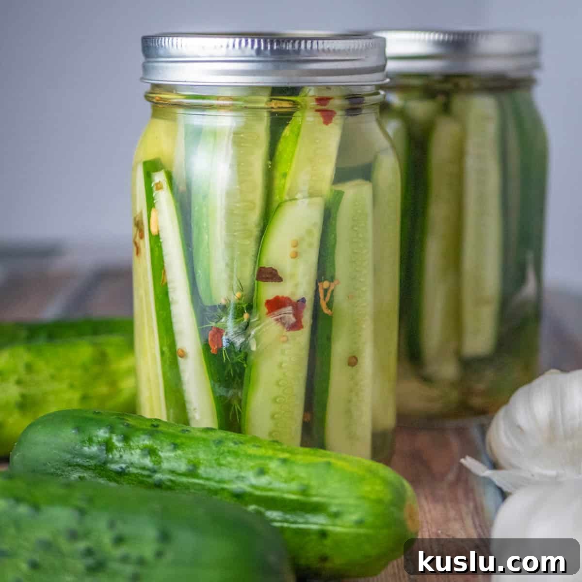 Quick Refrigerator Pickles: Simple No-Cook Dill Recipe 2 Jar of homemade refrigerator dill pickles with garlic and spices - Fresh cucumber spears pickling in a mason jar with red pepper flakes and dill. Quick and easy no-canning pickle recipe.