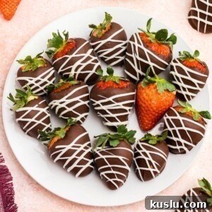 Chocolate covered strawberries on a white plate sitting on a pink table.