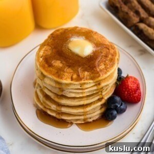 Golden gluten free pancakes stacked on a white plate.