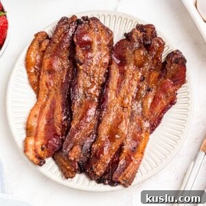Golden bacon slices on a white plate.