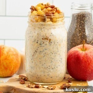 Creamy yogurt mixed with oats and apple slices in a mason jar making apple pie overnight oats.