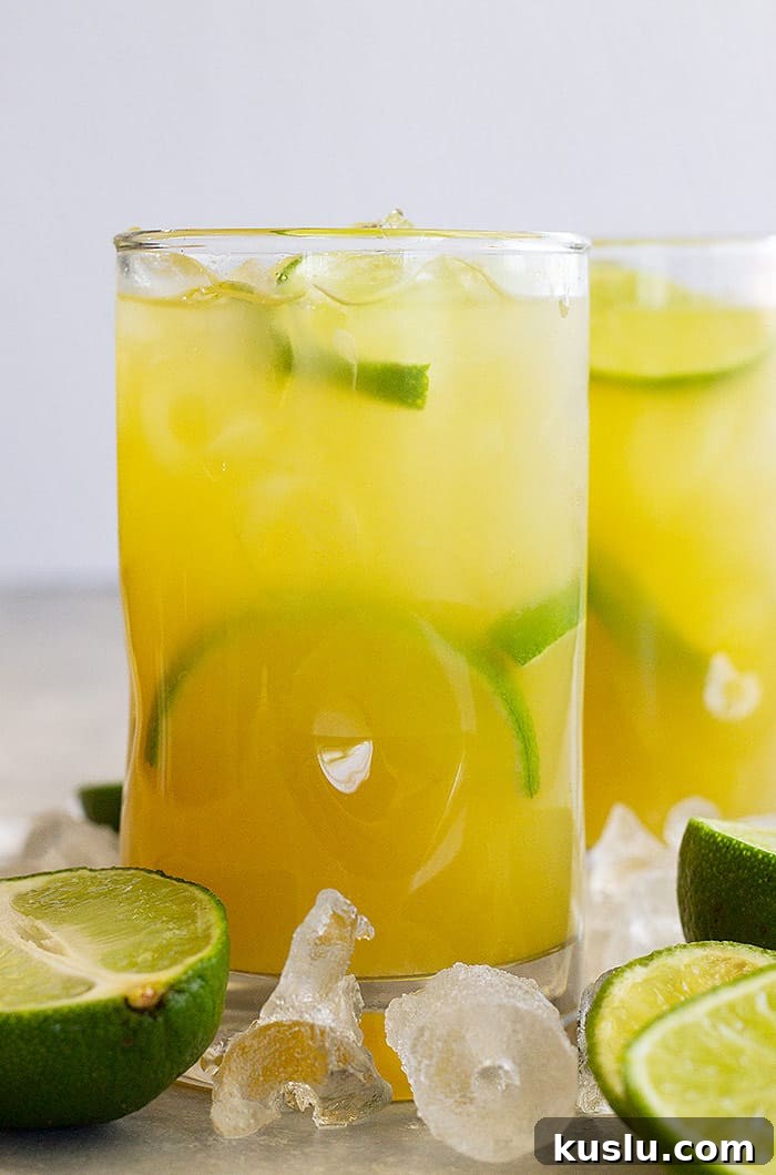 How to Make a Classic Margarita: Authentic Recipe & Tips 5 Tall glass of classic margarita with lime wedges and ice.
