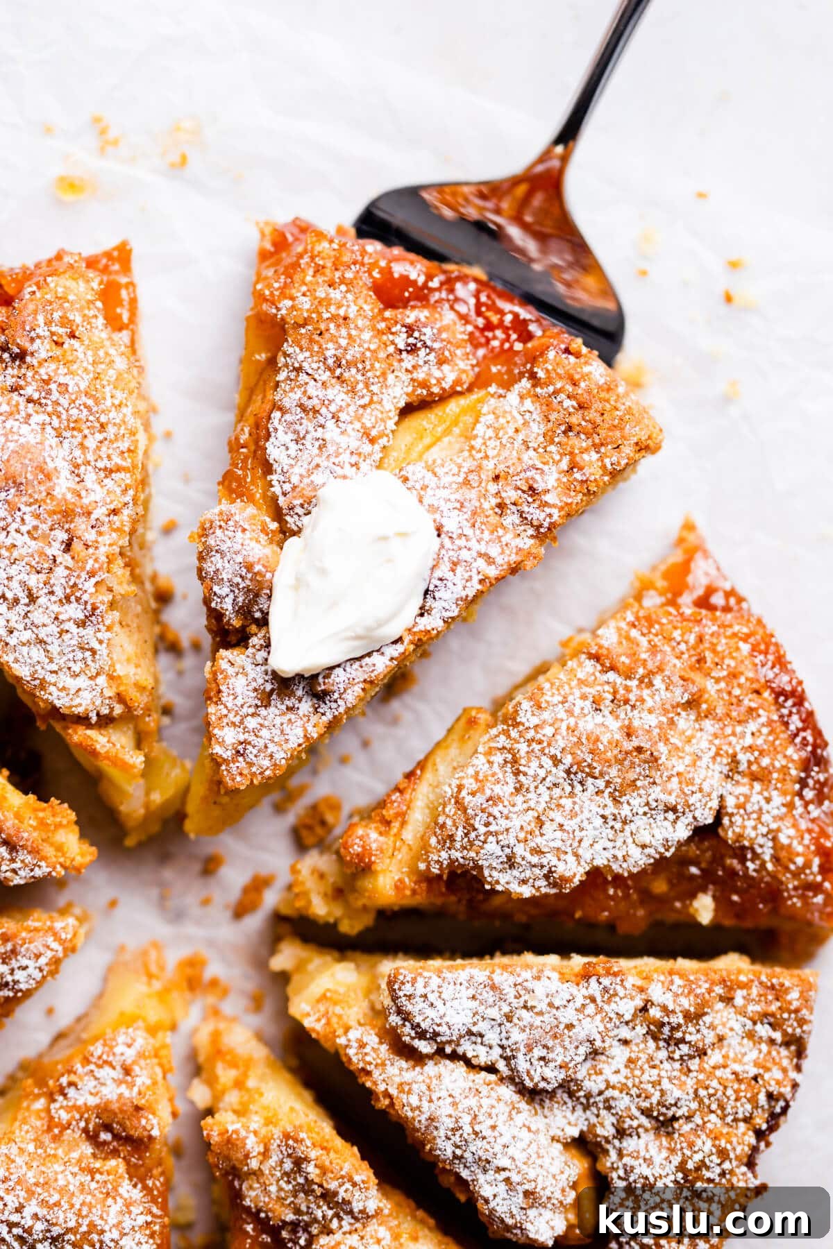 top view super close up at a slice of an apple cake topped with whipped cream