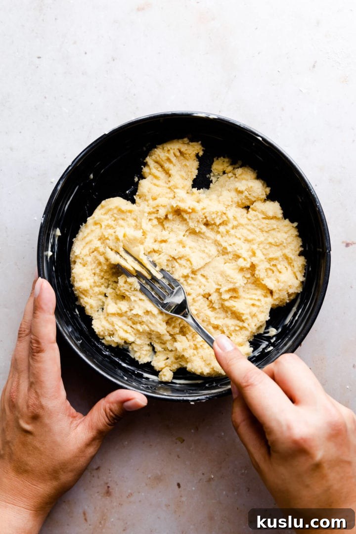 overhead view of a person spreading cake batter in the tin with the fork