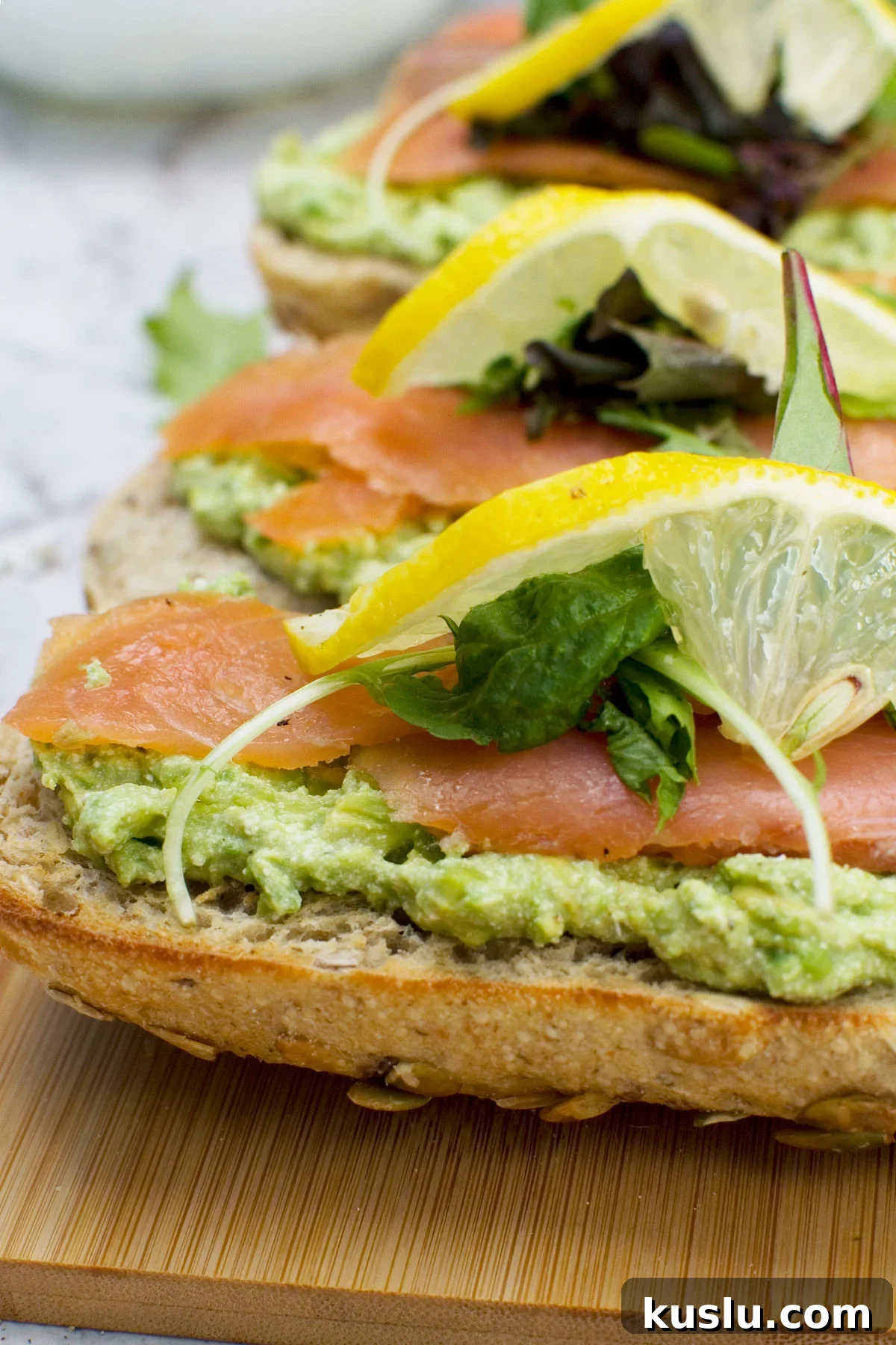 A close up of a wooden board of smoked salmon bruschetta with smashed avocado and feta
