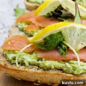 A close up of a wooden board of smoked salmon bruschetta with smashed avocado and feta