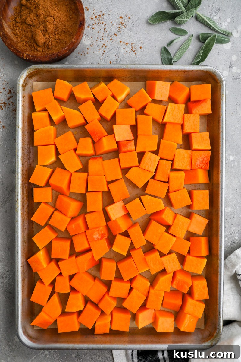 Maple Brown Butter Roasted Butternut Squash Recipe 6 A baking pan lined with parchment paper filled with diced butternut squash