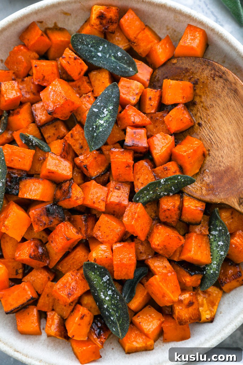 Maple Brown Butter Roasted Butternut Squash Recipe 8 A close up photo of roasted butternut squash tossed in maple brown butter and served with crispy sage leaves on top