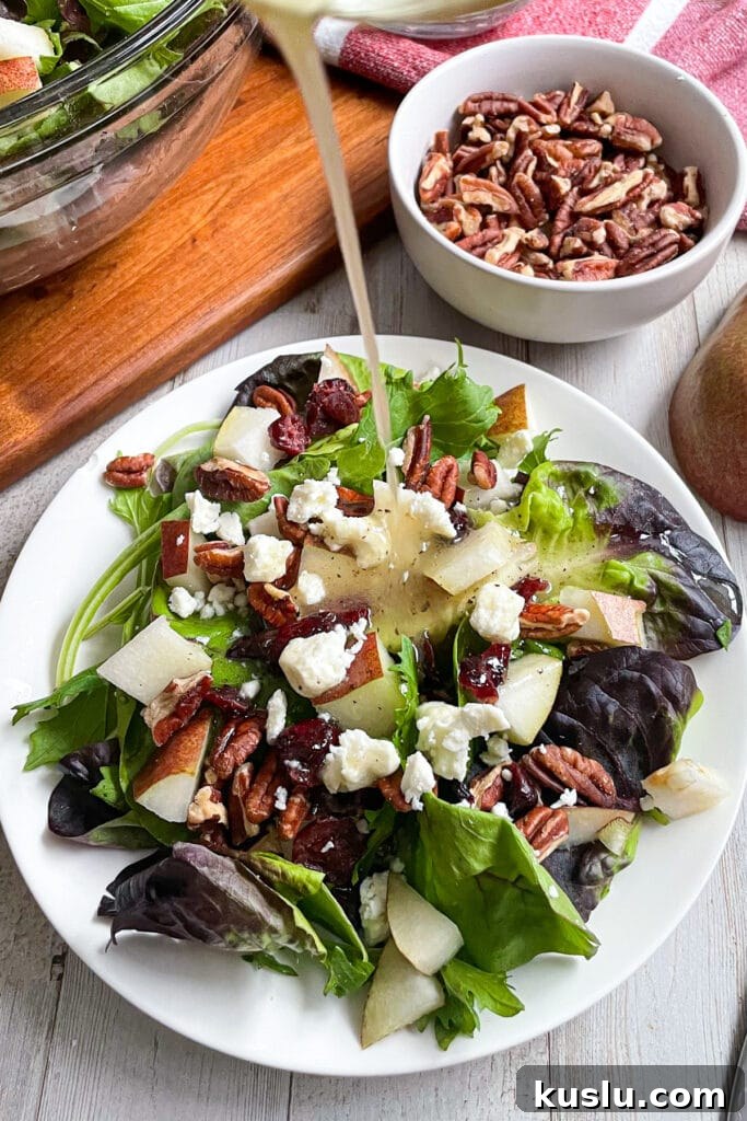 Autumn pear salad with honey mustard dressing being poured on top of salad