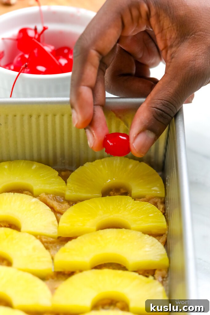 Classic Pineapple Upside-Down Cake Recipe with Caramelized Pineapple 4 man's hand adding cherries to pineapple cake