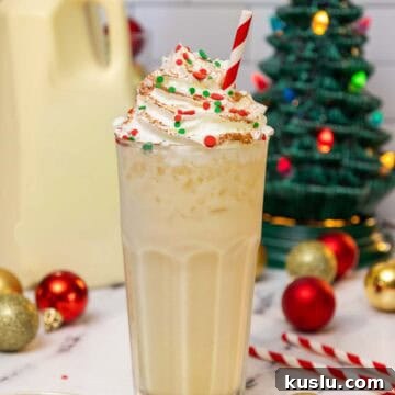 Holiday Eggnog Dirty Soda Recipe — Festive Creamy Cocktail 4 Tall glass of eggnog dirty soda topped with whipped cream, red and green holiday sprinkles, and a dusting of cinnamon, served with a red-striped straw.