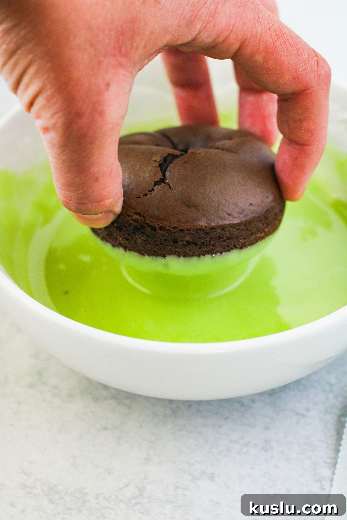 Spider Donuts Guide: How to Make Creepy Halloween Donuts 8 Dipping chocolate donut in green glaze in a bowl.